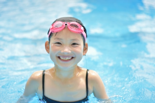 プールの中で水着を着た笑顔の子供