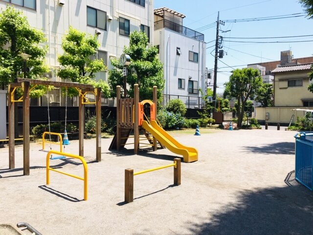 公園内に滑り台とブランコのある風景