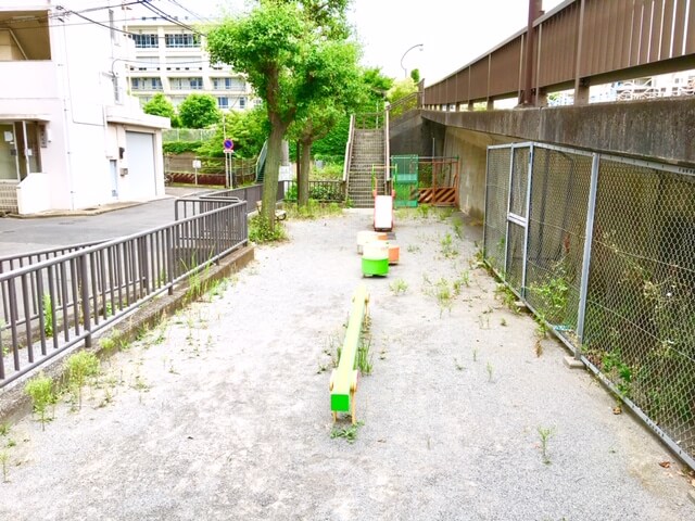 細長い公園内の中央にある滑り台と平均台