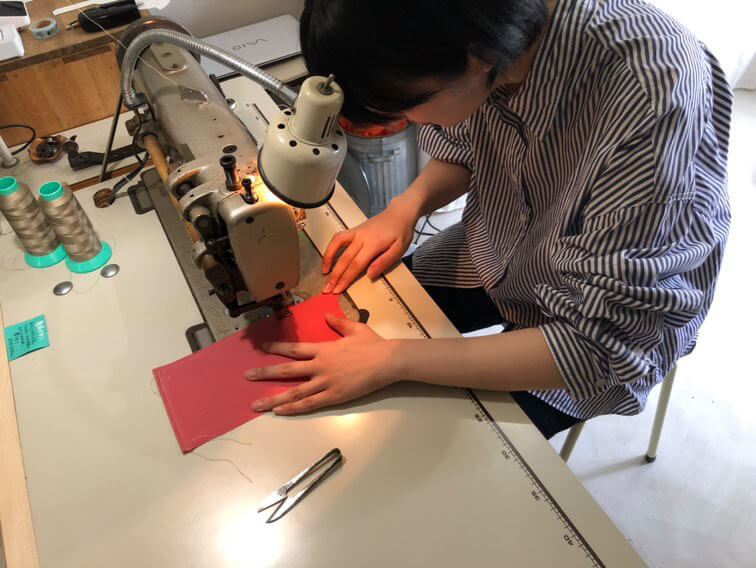 清洲寮の事務所にあるミシンでかばんを制作する女性オーナー