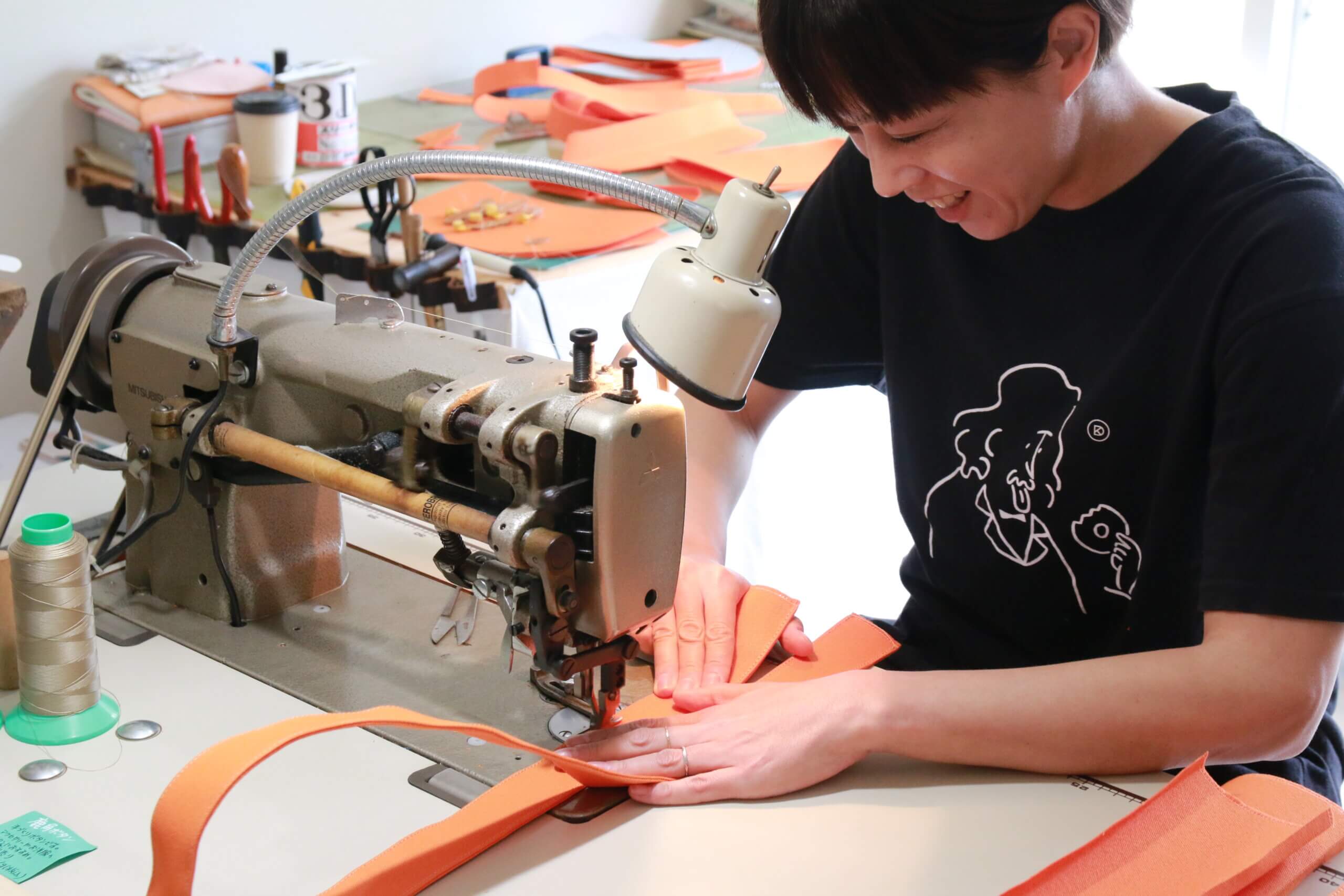 清洲寮の事務所にあるミシンでかばんを制作する女性オーナー