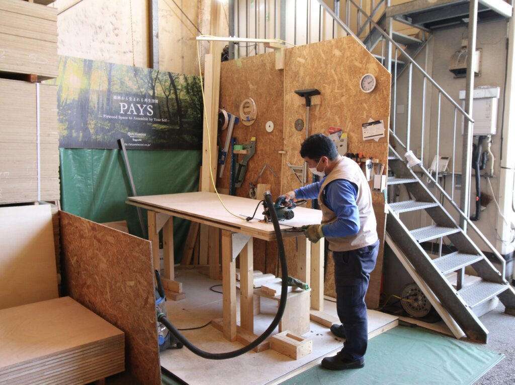 事務所横の作業場の合板を切る姿