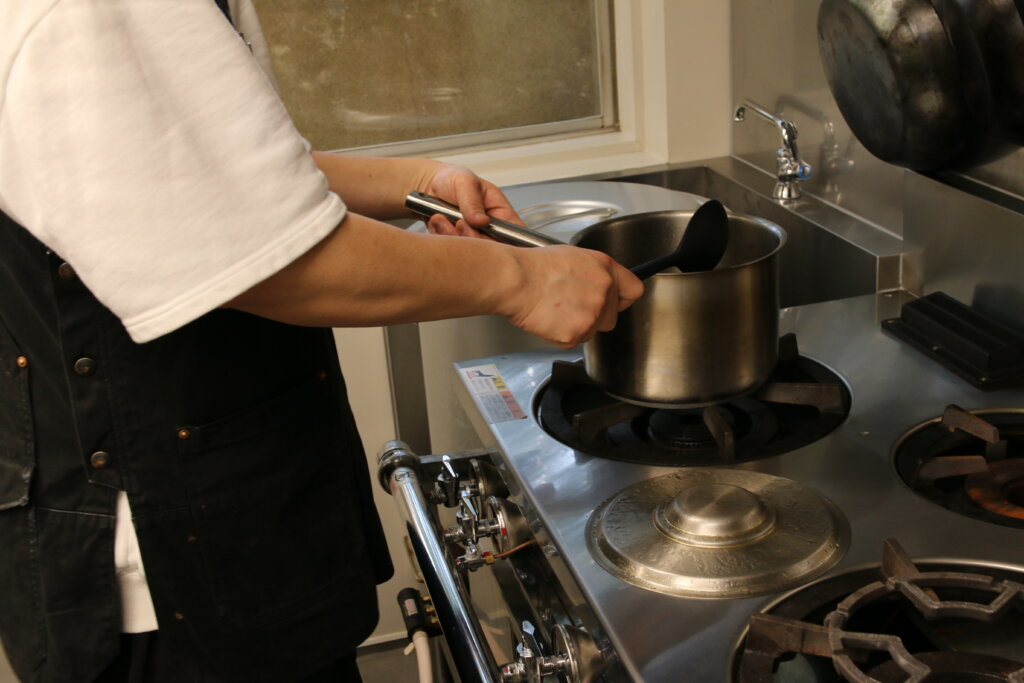 ガスコンロの鍋で調理するオーナー